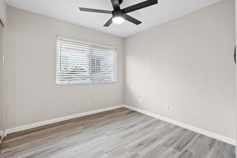 an empty bedroom with a ceiling fan and a window