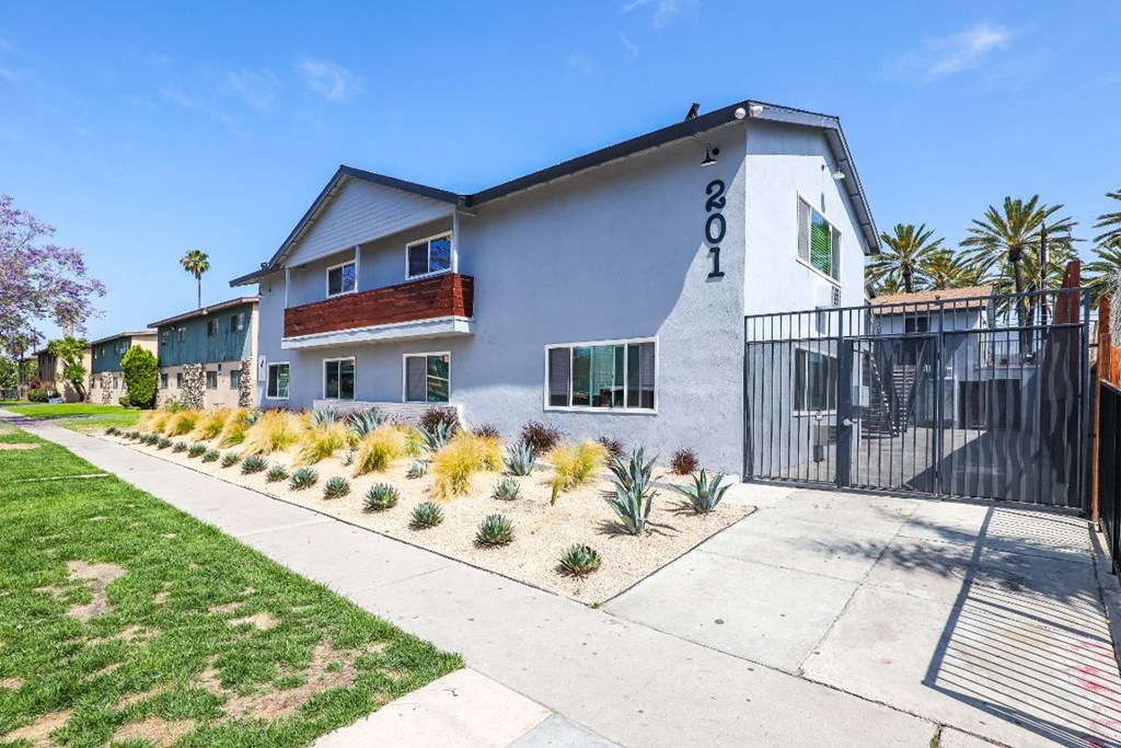 the front of a house with a sidewalk and a gate