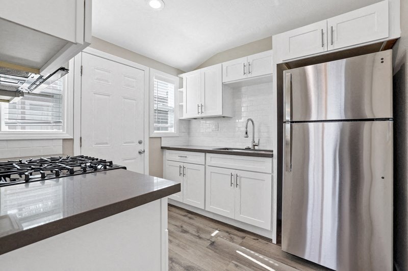 a kitchen with white cabinets and a stainless steel refrigerator at Huntington Manor Homes Apartment, California