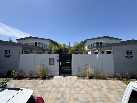 A white building with a black gate in front of it.