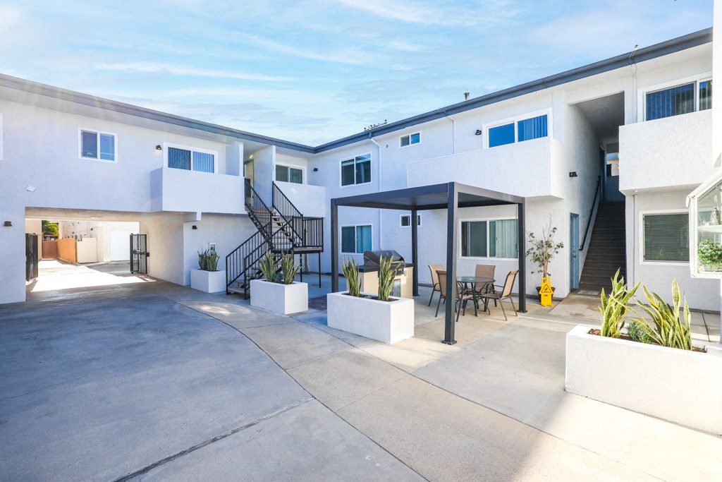 a white apartment building with a patio and a yellow fire hydrant