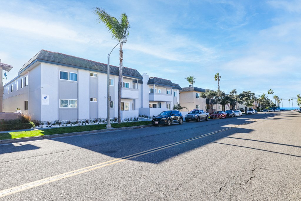 a row of white houses on the side of a street with cars parked in front