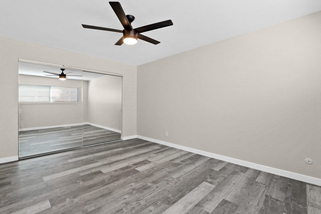 the living room of an empty home with a ceiling fan