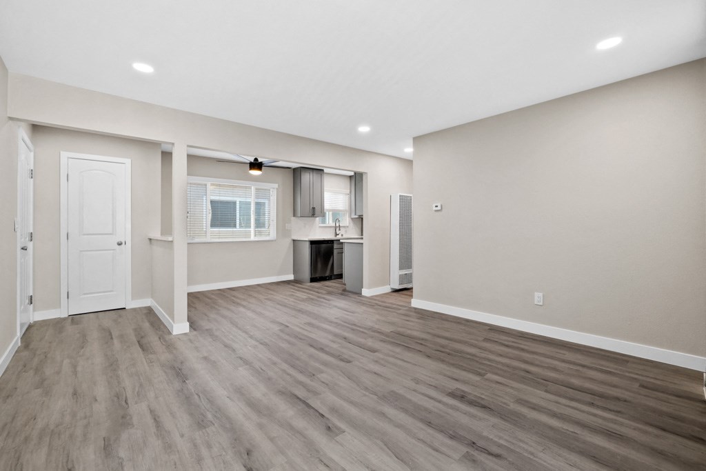 the living room and kitchen of a new home with white walls and wood flooring