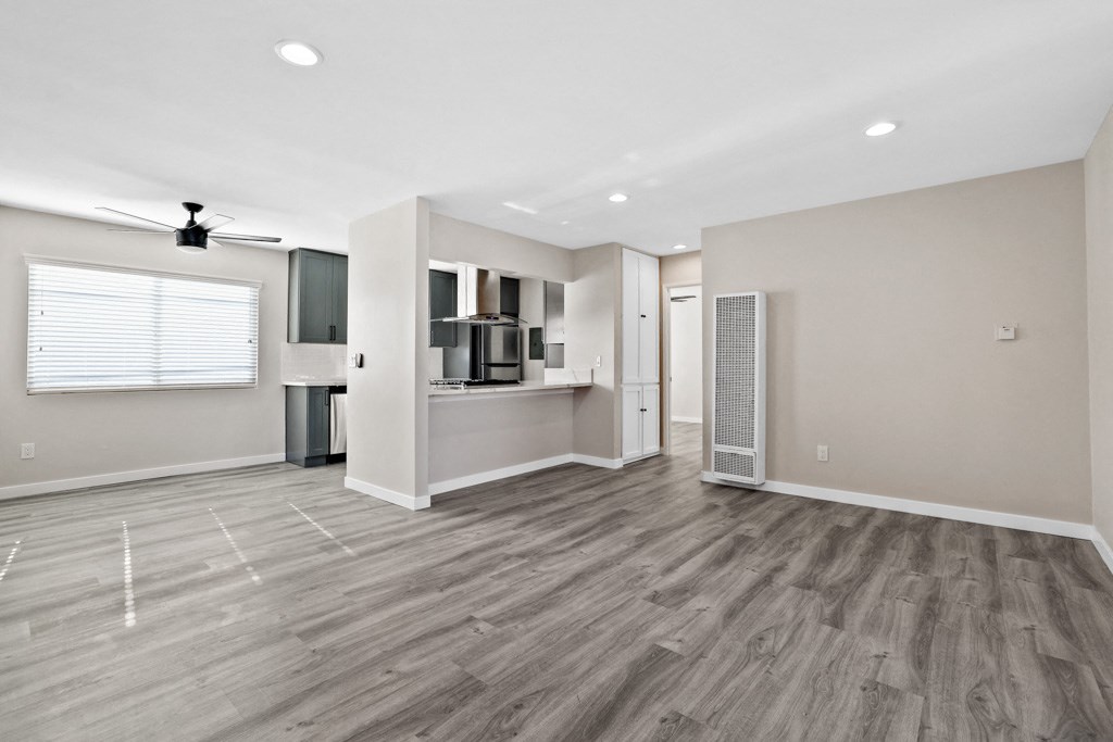 an empty living room with a kitchen and a window