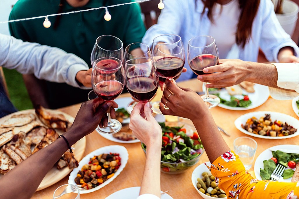 A group of people toasting with wine glasses at a dinner table at 325 on Seventeenth Apartments, Costa Mesa, CA