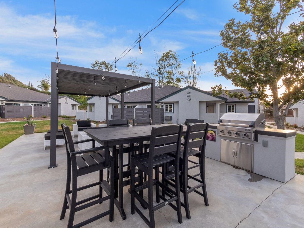 a patio with a table and chairs and a grill