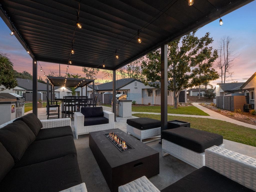 a covered patio with couches and a fire pit