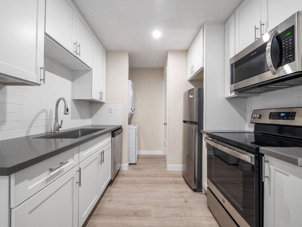 a kitchen with white cabinets and stainless steel appliances
