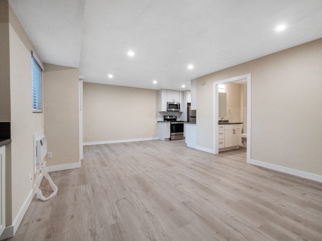 an empty living room with a kitchen in the background