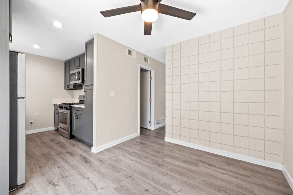 an empty kitchen with a ceiling fan and a refrigerator