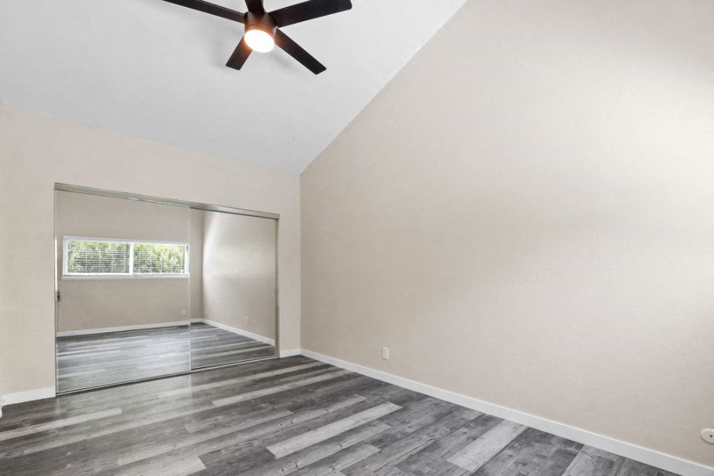 an empty living room with a ceiling fan and a window