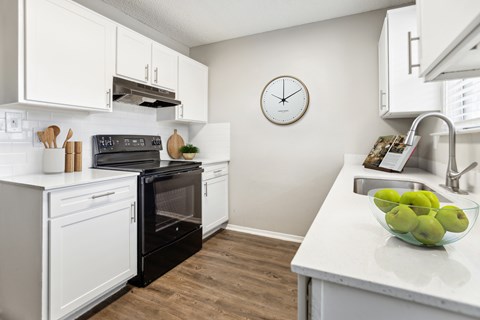 A kitchen with a black oven and white cabinets.