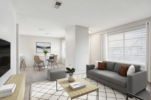 A living room with a grey couch, a coffee table, and a painting on the wall.
