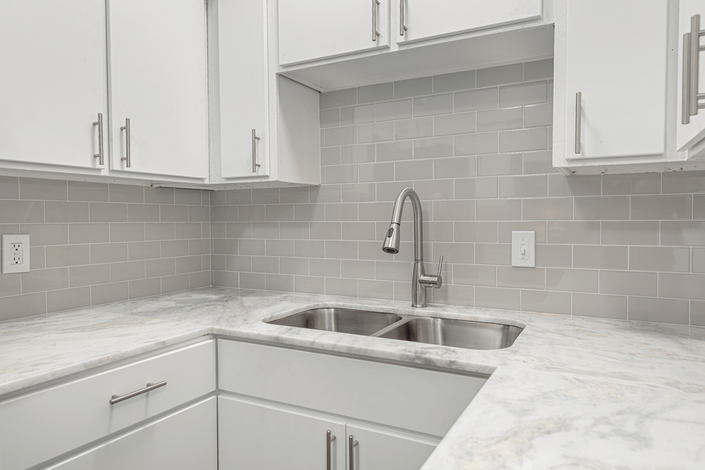 a white kitchen with a sink and white cabinets