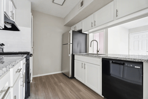 A kitchen with white cabinets and a black fridge.