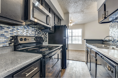 A kitchen with a black stove top oven and black cabinets.