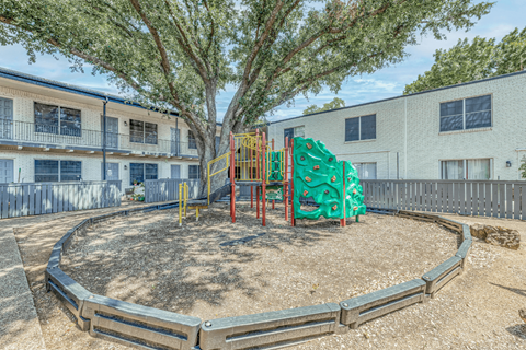 A playground with a green slide and a red and yellow structure.