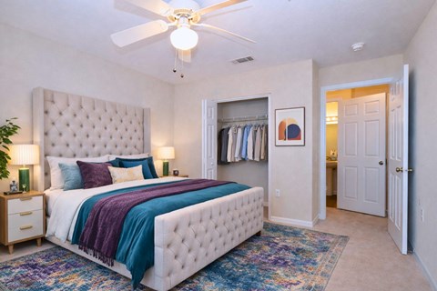 Master bedroom with tufted bed and ceiling fan at Walnut Ridge Apartments, Raleigh, North Carolina