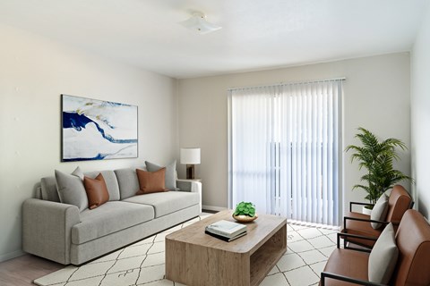 A living room with a grey couch, a coffee table, and a painting on the wall.