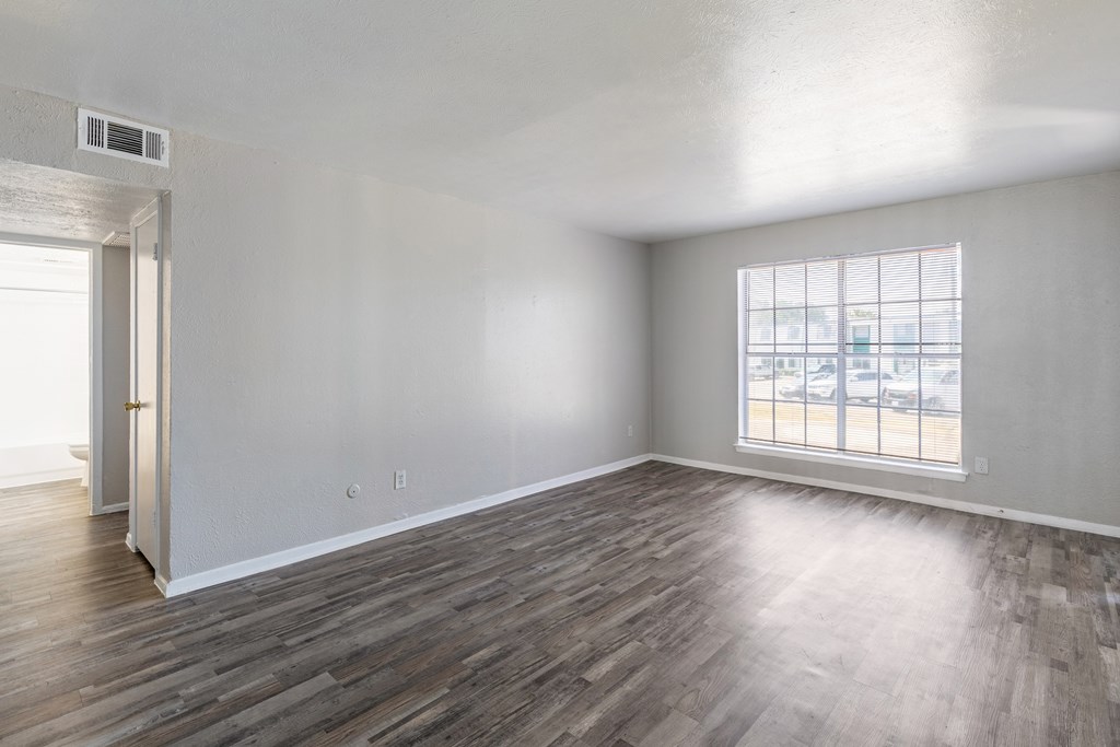 A room with wooden flooring and a window overlooking a parking lot.