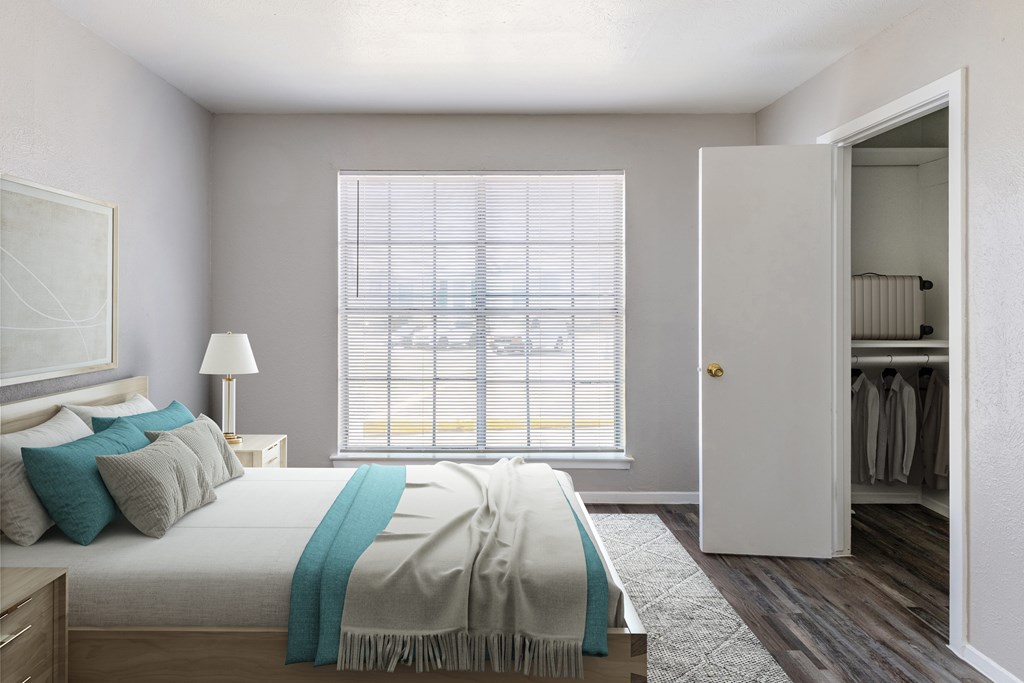 A bedroom with a large bed and a window with blinds.