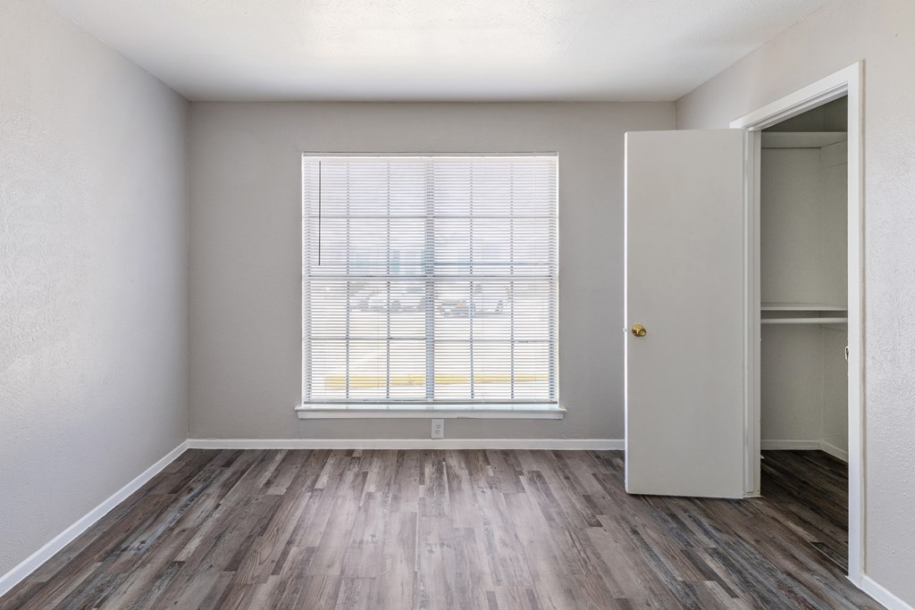 A room with a window and a wooden floor.