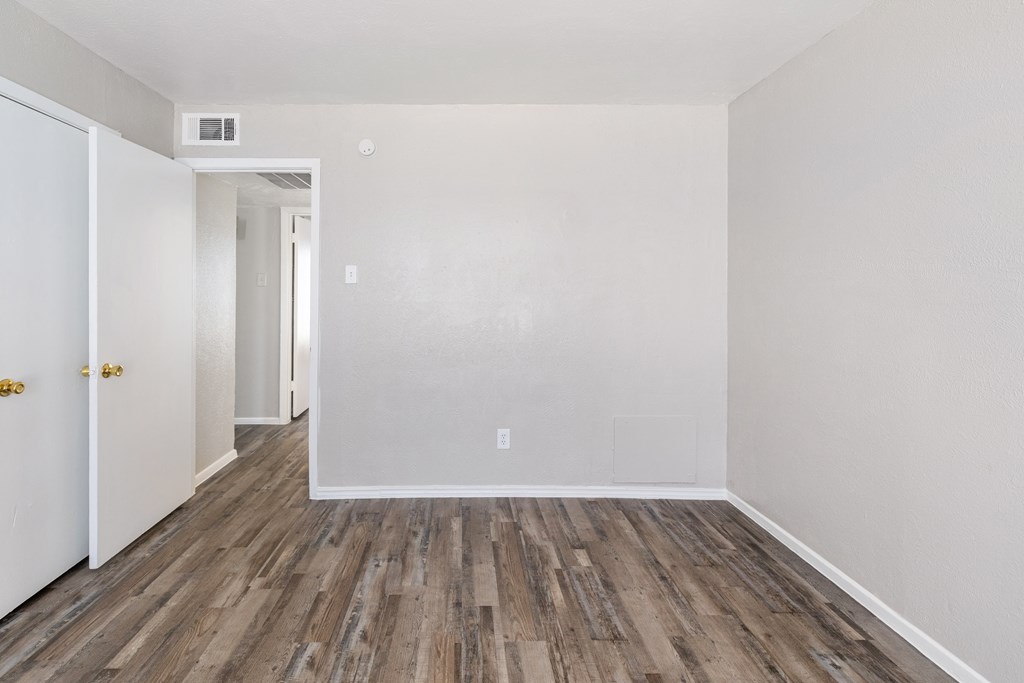 A room with wooden flooring and white walls.