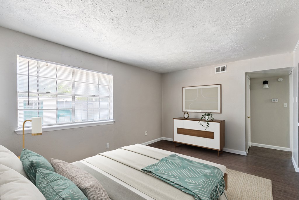 A bedroom with a bed, a nightstand, and a window.