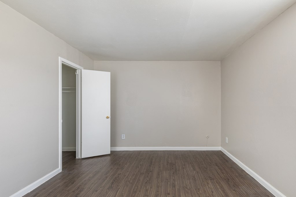 A room with a white door and wooden flooring.