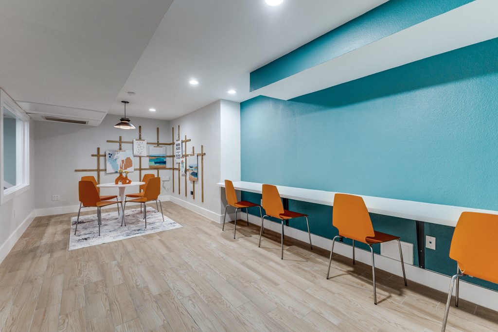 A room with orange chairs and a white table.