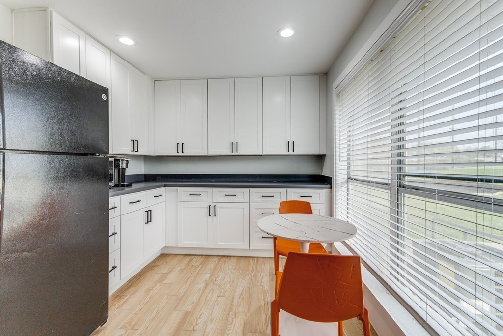 A kitchen with white cabinets and a black fridge.