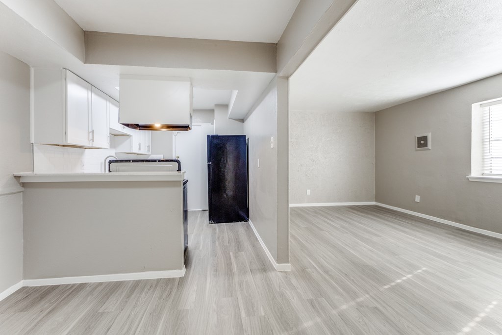 A spacious room with light grey walls and a wooden floor.