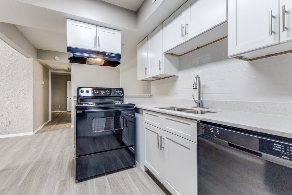 A modern kitchen with a black oven and white cabinets.