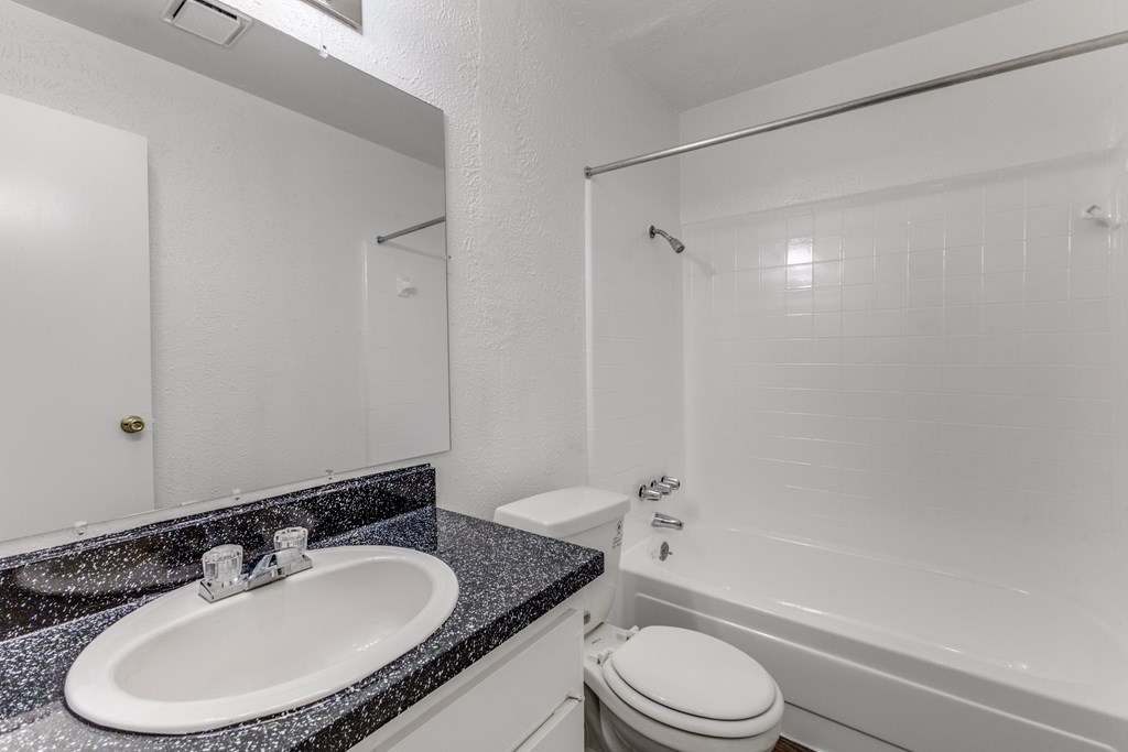 A white bathroom with a sink, toilet, and bathtub.