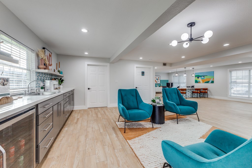 A kitchen with a white counter top and blue chairs.