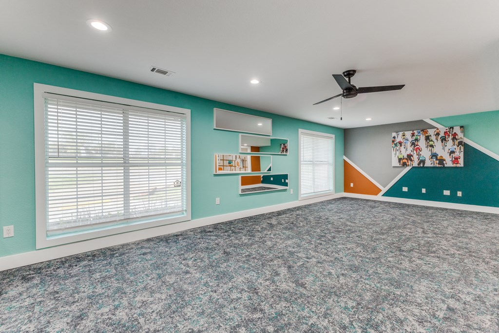 A room with a ceiling fan and a window with blinds.