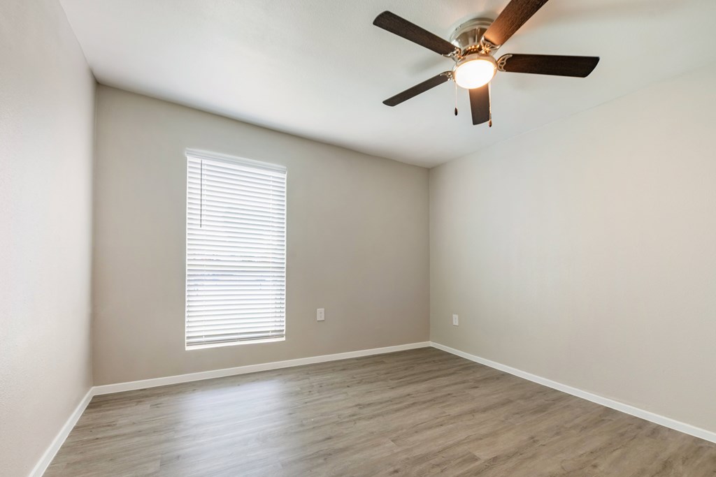 A room with a ceiling fan and a window with blinds.