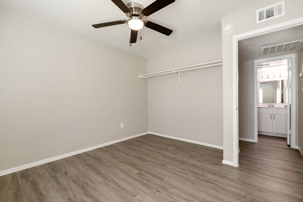 A room with a ceiling fan and light fixture, and a doorway leading to another room.