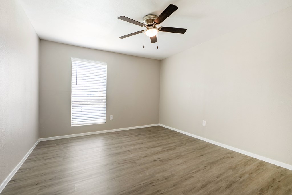 A room with a ceiling fan and a window with blinds.