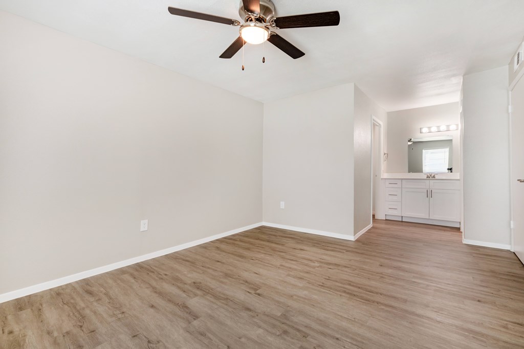 A room with a ceiling fan and wooden flooring.