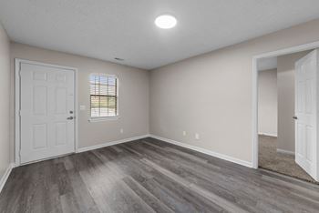 an empty living room with wood flooring and a white door