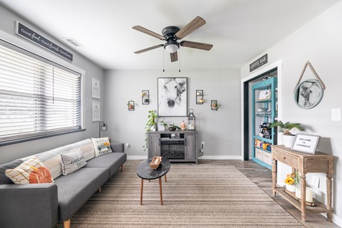 A living room with a grey couch, a coffee table, and a ceiling fan.
