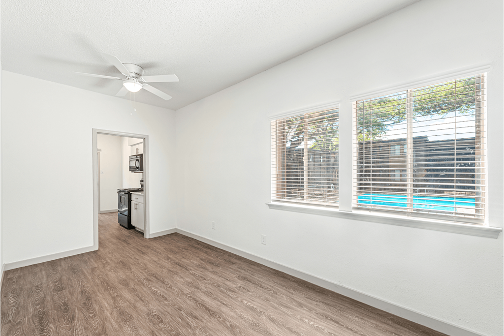 the living room of our studio apartment atrium with large windows and a ceiling fan
