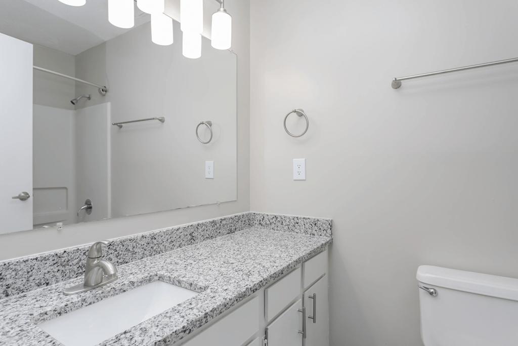 A bathroom with a sink, mirror, and bathtub.