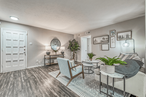 A living room with a grey sofa, a wooden chair, a coffee table, and a mirror on the wall.