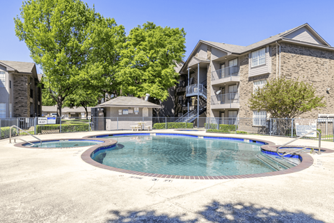 Swimming pool with surrounding apartments and landscaping at The Meadows Apartments, Garland, TX