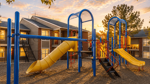A playground with a yellow slide and a blue structure.