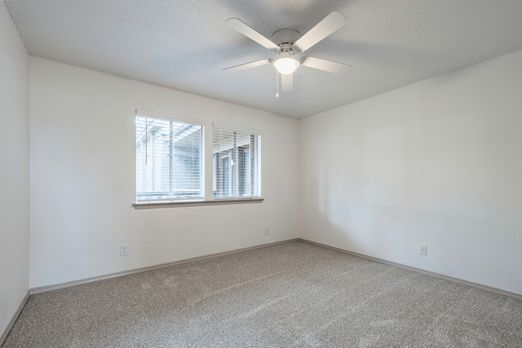 an empty room with a ceiling fan and a window