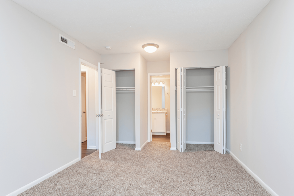 a spacious bedroom with closet doors and a carpeted floor at The Hudson, Fayetteville, North Carolina